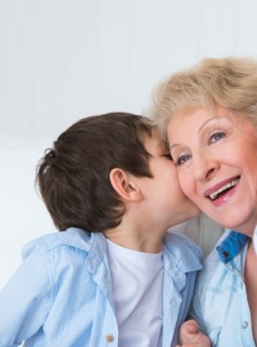 Grandmother with grandson having fun at home - whispering secret